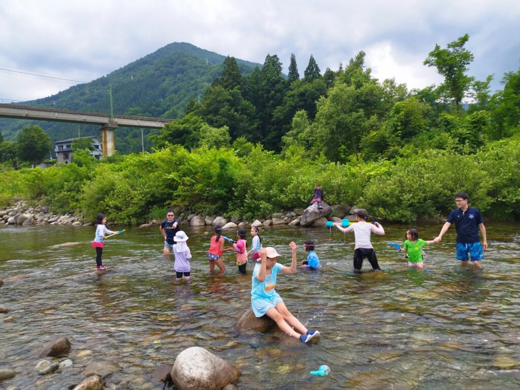 湯沢の魚沼川で川遊びをする大人と子ども